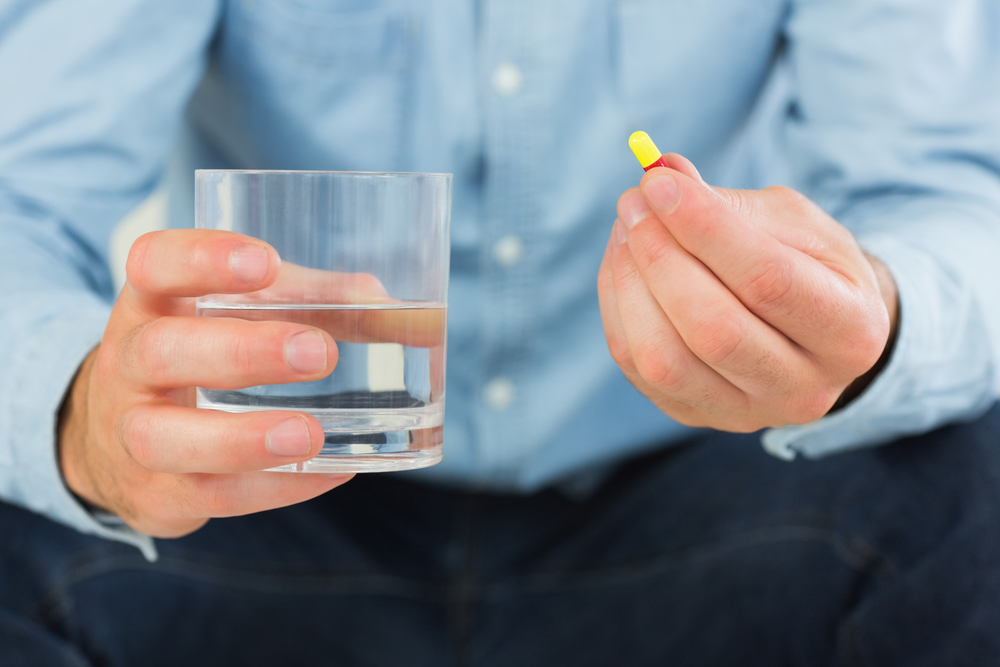 man taking antibiotic pill in thailand