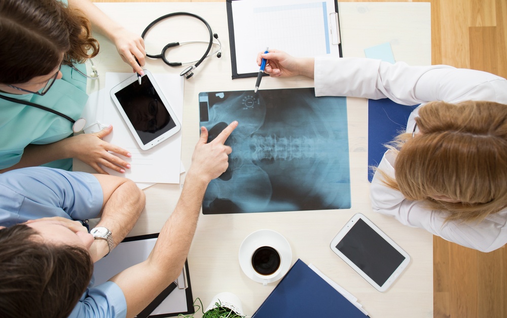 Doctors sitting around the table and interpreting x-ray image